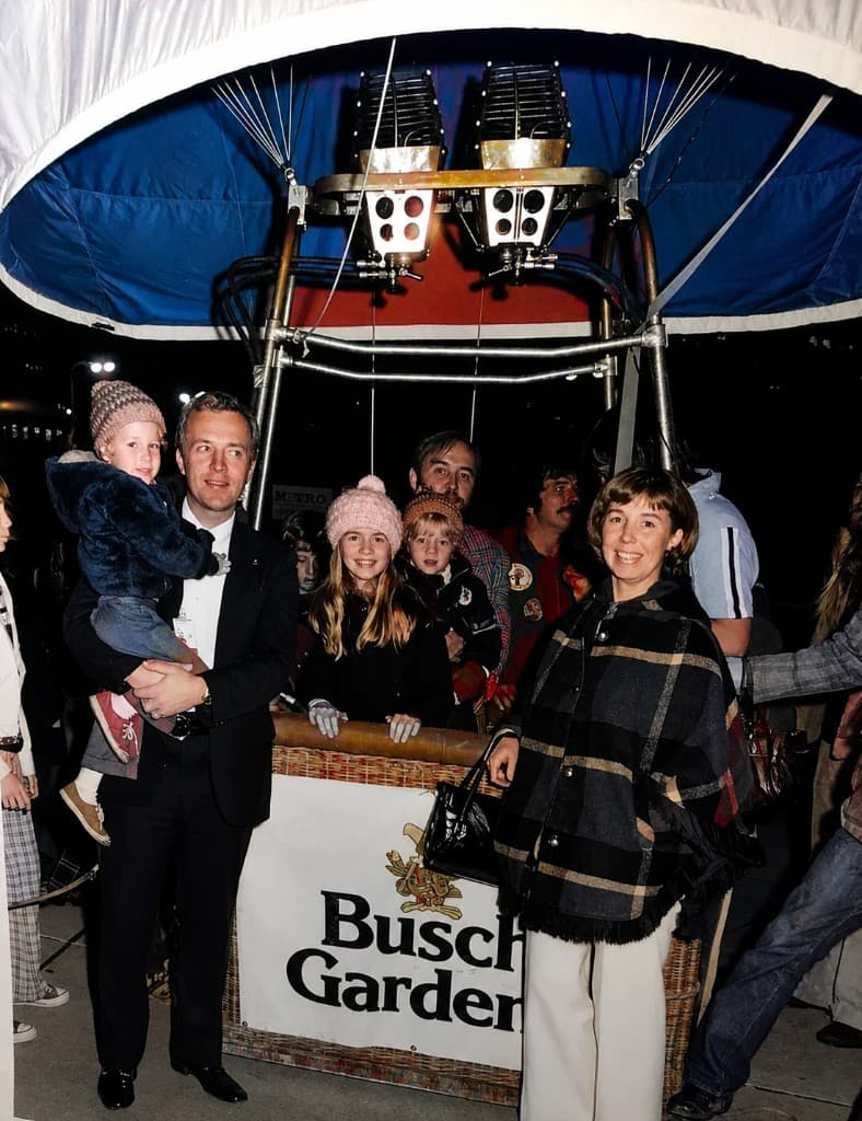 Children and adults gathered in and around a hot-air balloon basket with a Busch Gardens banner.